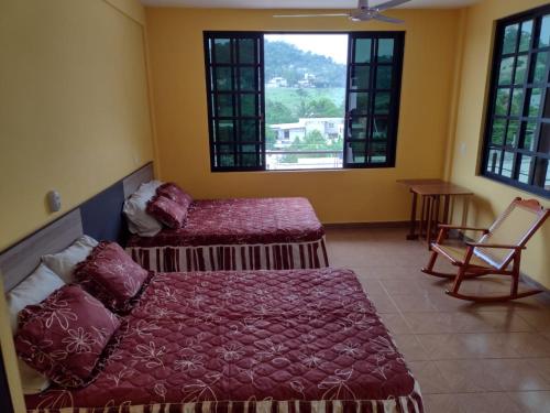 a bedroom with a bed and a chair and windows at El Rincón Preferido in Papantla de Olarte