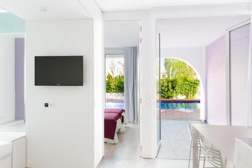 a white living room with a tv on a wall at Ebano Hotel Apartments & Spa in Playa d'en Bossa