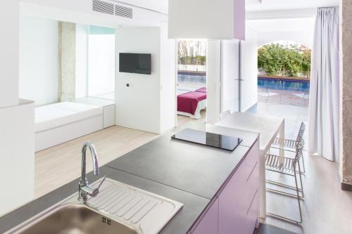 a kitchen with a sink and a tv in a room at Ebano Hotel Apartments & Spa in Playa d'en Bossa