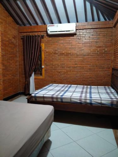 um quarto com 2 camas e uma parede de tijolos em Guesthouse Jogja Omah Punagi em Sleman