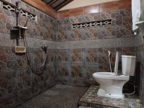 uma casa de banho com um WC e um chuveiro em Guesthouse Jogja Omah Punagi em Sleman