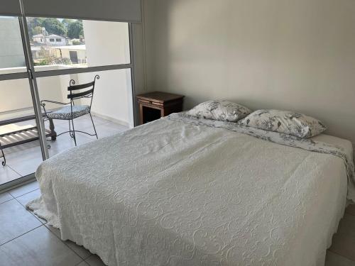 a bedroom with a bed and a chair and a window at Departamento con Vista a los cerros con Asador in Yerba Buena