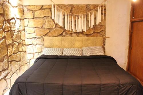 a bed in a room with a stone wall at DEPARTAMENTO CENTRO SAN CRISTOBAL Estacionamiento lugares publicos en la calle in San Cristóbal de Las Casas