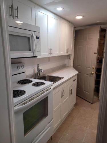 a kitchen with white cabinets and a stove and microwave at Noble Waterfront Suites in Brockville
