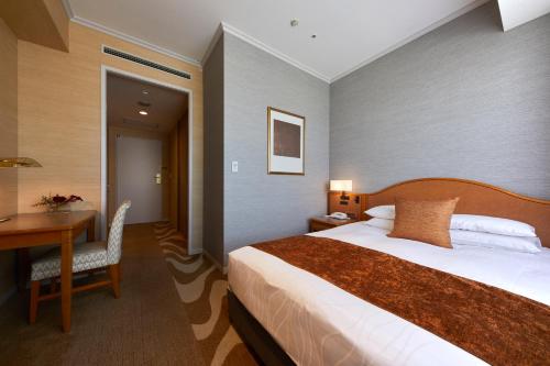 a hotel room with a bed and a desk and a table at Hotel Nikko Kanazawa in Kanazawa