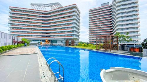 a swimming pool with two tall buildings in the background at REOTEL at Kaina Tower - The Nove in Telukmataikan