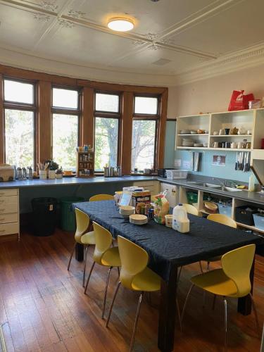 a kitchen with a table with yellow chairs in it at Manor house backpackers in Dunedin