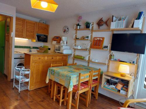 une cuisine avec une table et des chaises ainsi qu'une télévision dans l'établissement Appartement cosy au cœur d'Autrans, 100m des pistes, balcon, 28m², 4 pers, bien équipé, 2 étoiles - FR-1-737-36, à Autrans