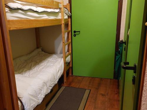 une chambre avec deux lits superposés et une porte verte dans l'établissement Appartement cosy au cœur d'Autrans, 100m des pistes, balcon, 28m², 4 pers, bien équipé, 2 étoiles - FR-1-737-36, à Autrans