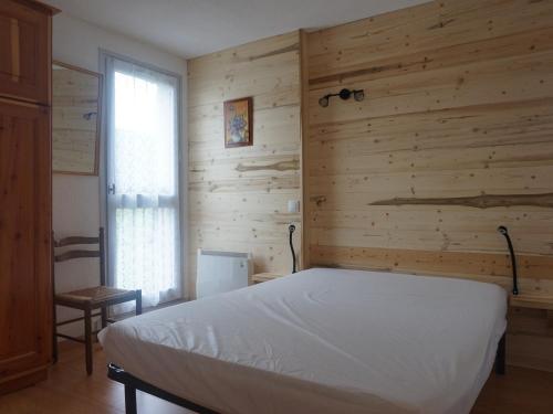 um quarto com uma cama e uma parede de madeira em Appartement Méaudre, 2 pièces, 4 personnes - FR-1-737-6 em Méaudre