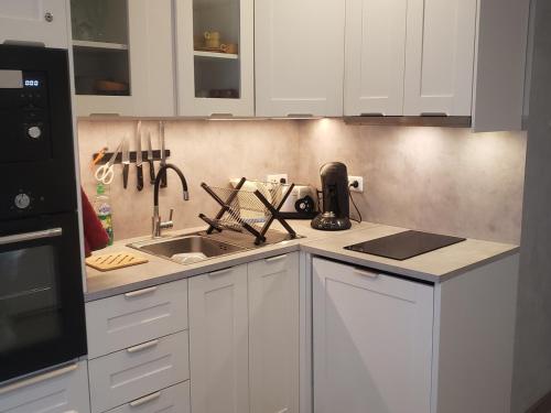 une cuisine avec des armoires blanches et un évier dans l'établissement Charmant studio rénové avec balcon, proche navette ski et village, parking privé - 4 pers, Autrans - FR-1-737-8, à Autrans