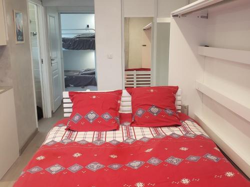 une petite chambre avec des oreillers rouges et un lit dans l'établissement Charmant studio rénové avec balcon, proche navette ski et village, parking privé - 4 pers, Autrans - FR-1-737-8, à Autrans