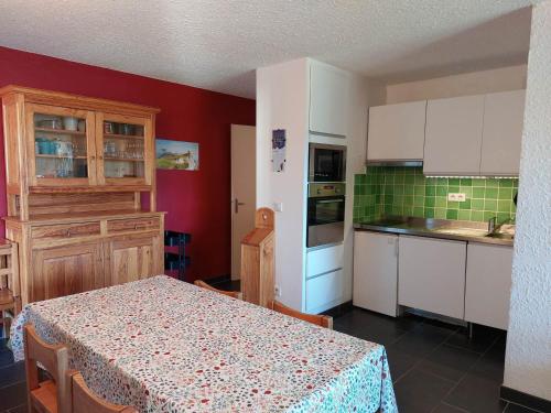 une cuisine avec une table et des placards blancs dans l'établissement Appartement cosy 3 étoiles, 8 pers, 53 m², proche centre et pistes, balcon sud/ouest, parking privé - FR-1-737-13, à Autrans