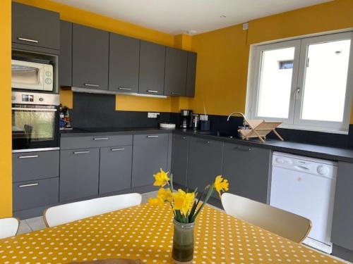 - une cuisine avec une table ornée de fleurs jaunes dans l'établissement Belle Maison à Autrans, 4 Chambres, 8 Pers, Jardin, Proche Village et Pistes de Ski - FR-1-737-14, à Autrans