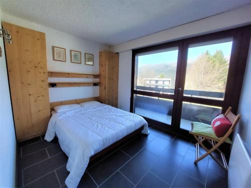a bedroom with a bed and a large window at Appartement cosy 3 étoiles, 8 pers, 53 m², proche centre et pistes, balcon sud/ouest, parking privé - FR-1-737-13 in Autrans