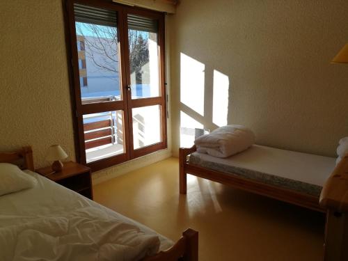 - une chambre avec 2 lits et une fenêtre ouverte dans l'établissement Charmant T3 avec Balcon Sud à 650m du Centre et des Pistes à Autrans - 6 Pers, Parking, Animaux OK - FR-1-737-35, à Autrans