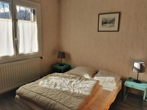 Ce lit se trouve dans une chambre avec 2 tables et une fenêtre. dans l'établissement Appartement à Autrans - 57 m², 4 pers, proche centre et pistes de ski - FR-1-737-60, à Autrans