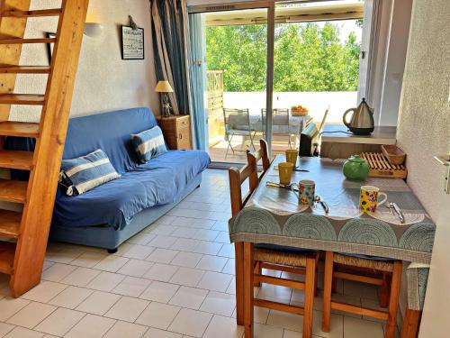 un salon avec un canapé bleu et une table dans l'établissement Appartement 6 pers, accès direct plage, proche commerces, terrasse, parking, Wi-Fi optionnel - FR-1-387-199, à Marseillan