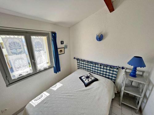 - une petite chambre avec un lit et une lampe bleue dans l'établissement Appartement 6 pers, accès direct plage, proche commerces, terrasse, parking, Wi-Fi optionnel - FR-1-387-199, à Marseillan
