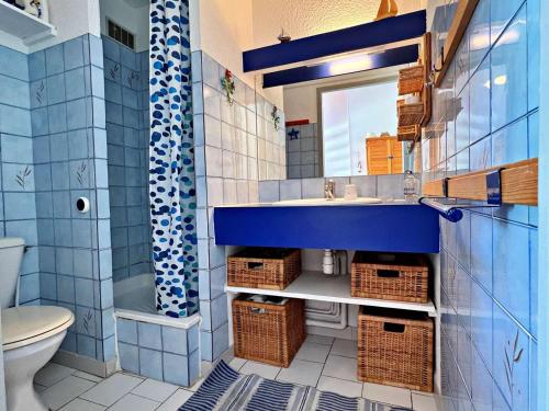 une salle de bain bleue avec un lavabo et un miroir dans l'établissement Appartement 6 pers, accès direct plage, proche commerces, terrasse, parking, Wi-Fi optionnel - FR-1-387-199, à Marseillan