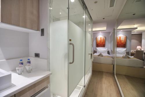 a bathroom with a shower and a bedroom at The Mini Suites Eton Tower Makati in Manila