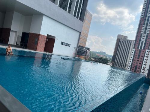 a man sitting on the edge of a swimming pool on a building at Chambers Couple studio 424 in Kuala Lumpur