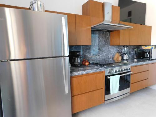 a stainless steel refrigerator in a kitchen with wooden cabinets at Oasis Urban Retreat in Cancún