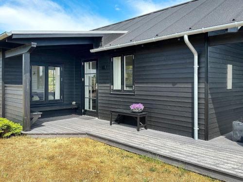 une maison noire avec une véranda dotée d'un banc et de fleurs dans l'établissement 6 person holiday home in Hadsund, à Hadsund