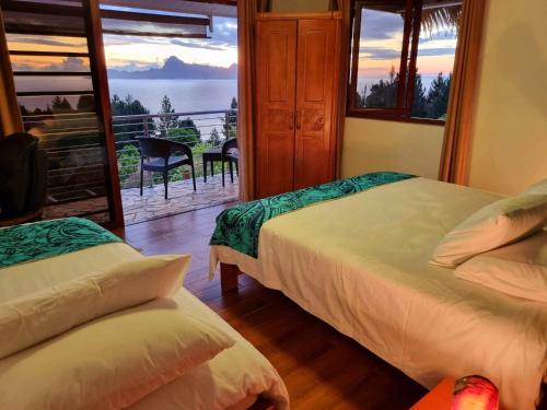 two beds in a room with a view of the ocean at Tahiti Hills Lodge in Punaauia