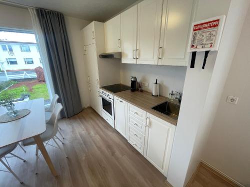 una pequeña cocina con armarios blancos y una mesa en Cosy Studio Apartment en Hveragerði