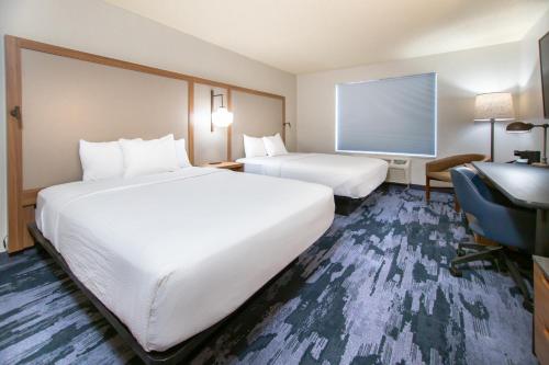 a hotel room with two beds and a desk at Fairfield Inn & Suites Rapid City in Rapid City