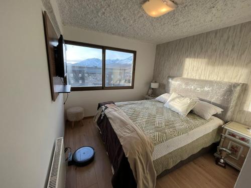 a bedroom with a bed with a television and a window at Ski in-out Apartment in El Colorado in El Colorado
