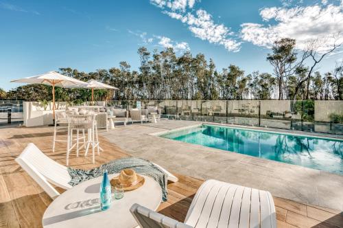 a swimming pool with a table and chairs next to a pool at Essence Peregian Beach in Peregian Beach