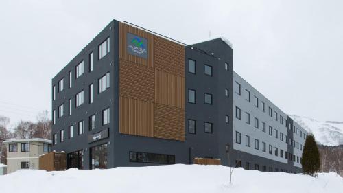 um edifício com um sinal no lado dele na neve em Always Niseko em Niseko