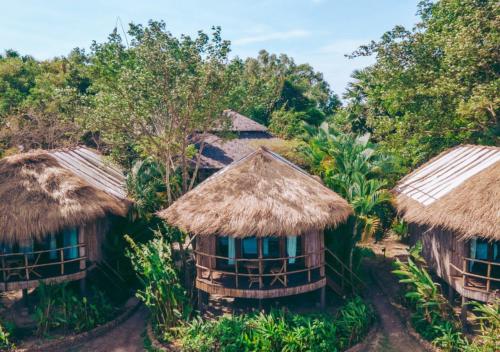 a group of huts with thatched roofs and trees at Devi Kampot Resort at Phum Kampot in Kampot