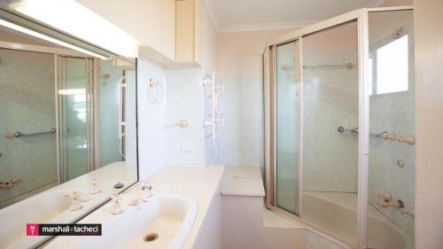 La salle de bains blanche est pourvue d'une douche et d'un lavabo. dans l'établissement Aberdeen Unit 1 Bermagui, à Bermagui