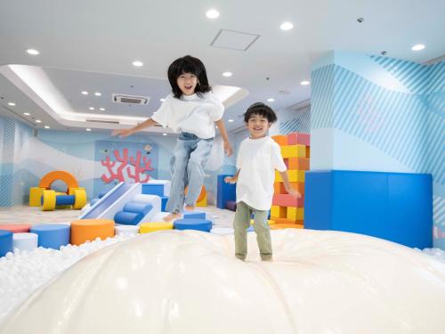 una chica y un chico saltando sobre una sala de juegos en Irago Ocean Resort, en Tahara