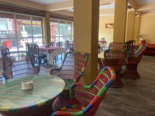 um restaurante com mesa, cadeiras, mesas e janelas em Prashiddha Resort em Dakshīnkāli