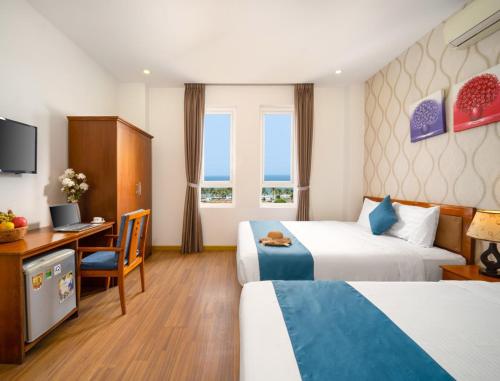 ein Hotelzimmer mit 2 Betten und einem Schreibtisch in der Unterkunft Shara Hotel Da Nang in Đà Nẵng
