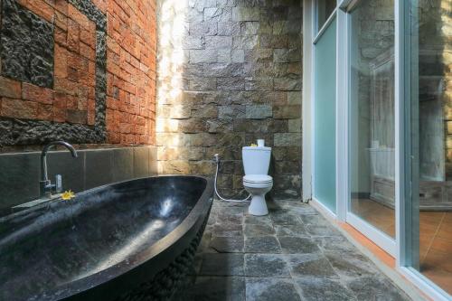 La salle de bains est pourvue d'une baignoire et de toilettes. dans l'établissement Diuma residence yoga meditation retreat and healing Center, à Denpasar