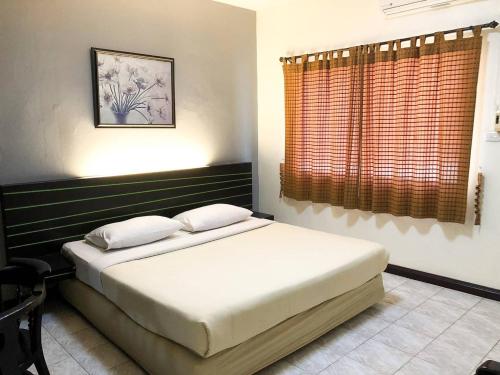 een slaapkamer met een bed en een raam bij Suansin Garden Hotel โรงแรมสวนสินการ์เด้น in Tak