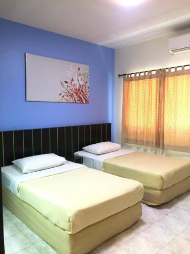 two beds in a room with blue walls at Suansin Garden Hotel โรงแรมสวนสินการ์เด้น in Tak