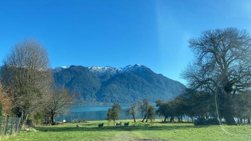 a field with trees and a lake and mountains at Cabaña visión in Puerto Montt