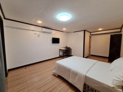 a bedroom with a white bed and a desk at Hideaways Restobar and Resort in Laguindingan