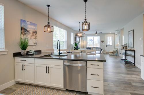 une cuisine avec des armoires blanches et un évier et un salon dans l'établissement Queen Tide Cottage, à Ocean Shores