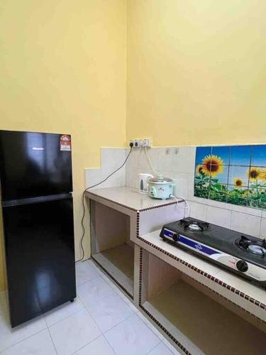 a small kitchen with a stove and a refrigerator at Hajjah Homestay Jln Rajawali Tg Agas in Muar