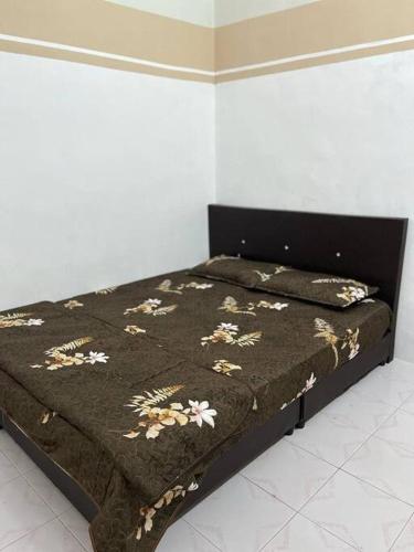 a bed with a brown blanket with flowers on it at Hajjah Homestay Jln Rajawali Tg Agas in Muar