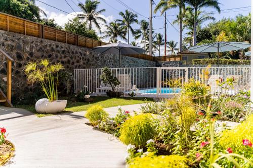 un giardino con piscina e alcune piante e ombrelloni di Résidence Touristique LES MASCARINS a Petite-Île