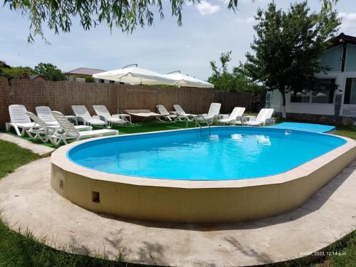 a large swimming pool with chairs and a table at Pensiunea Cristian in Murighiol