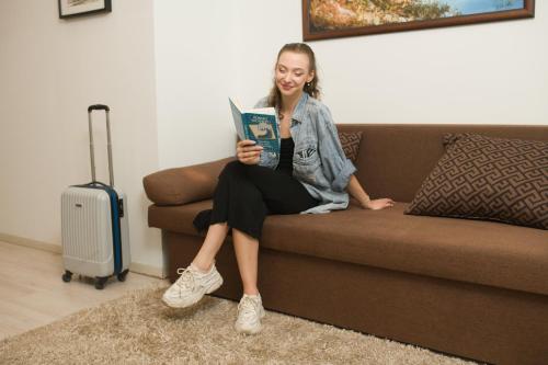 una mujer sentada en un sofá leyendo un libro en Goldcentral Apartment Dob en Budapest